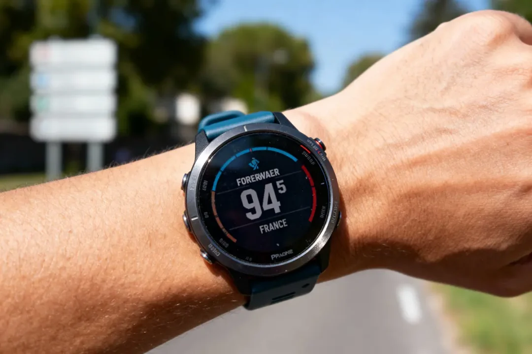 Montre connectée sur poignet, affichant Forewear 94.5 France, en extérieur avec route floue en arrière-plan.