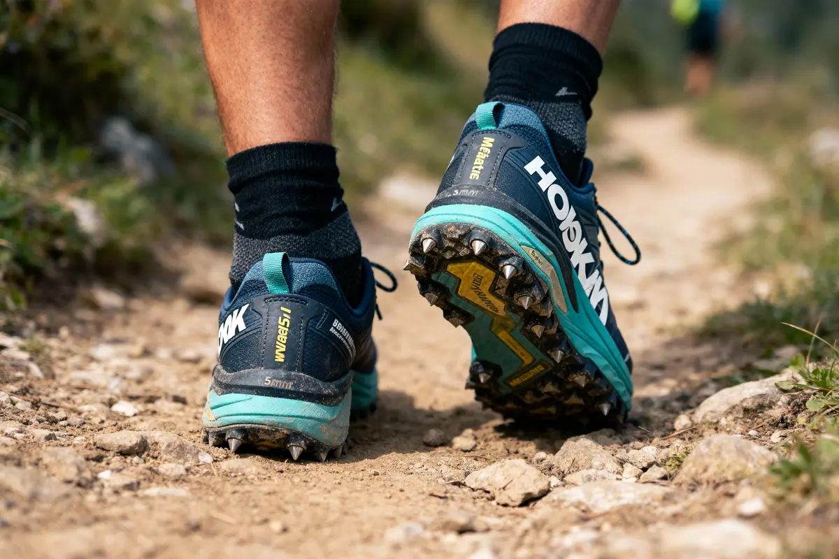 Une personne marchant sur un sentier naturel avec des chaussures de trail à crampons visibles.