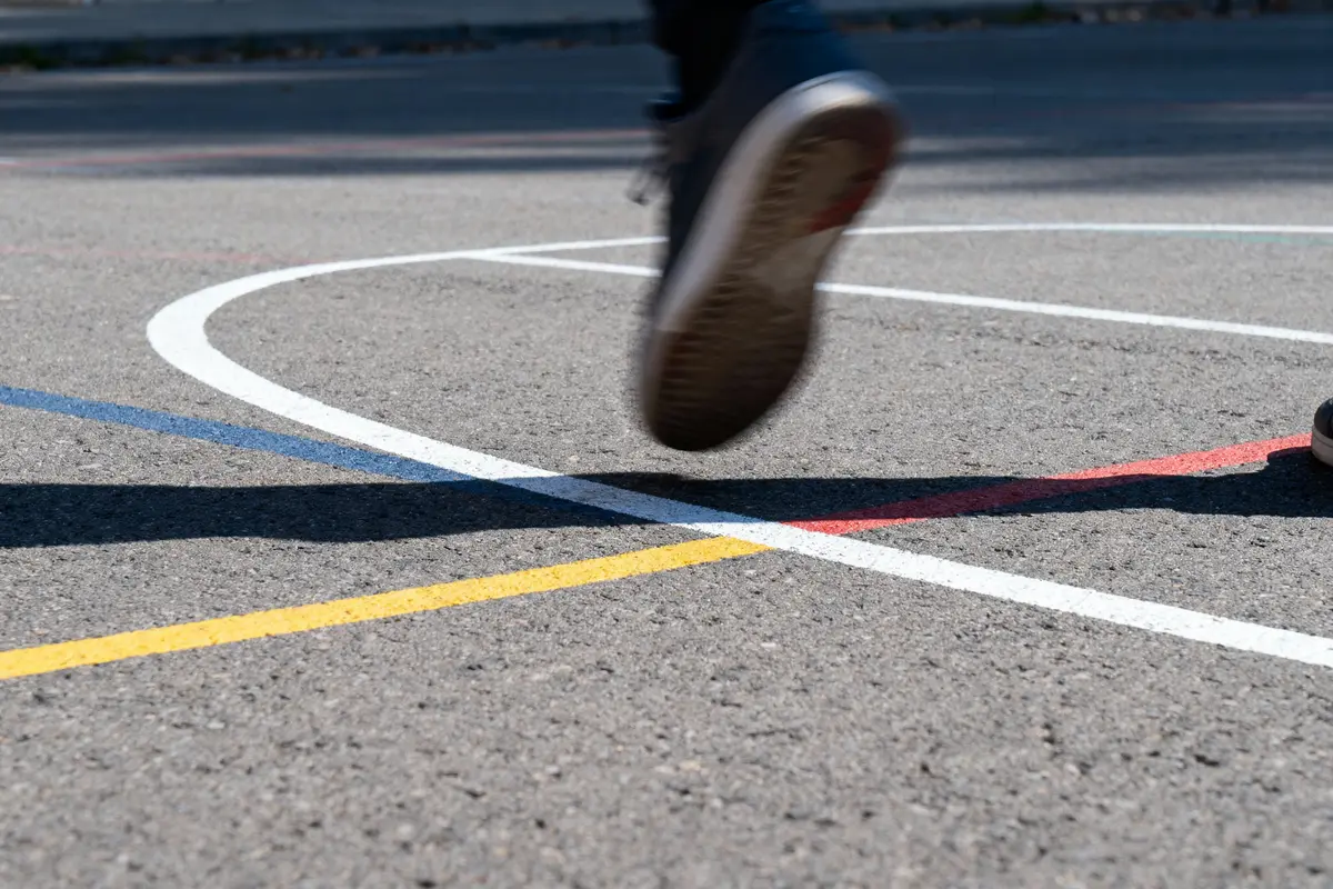 Personne courant sur un terrain de sport avec lignes colorées tracées au sol.