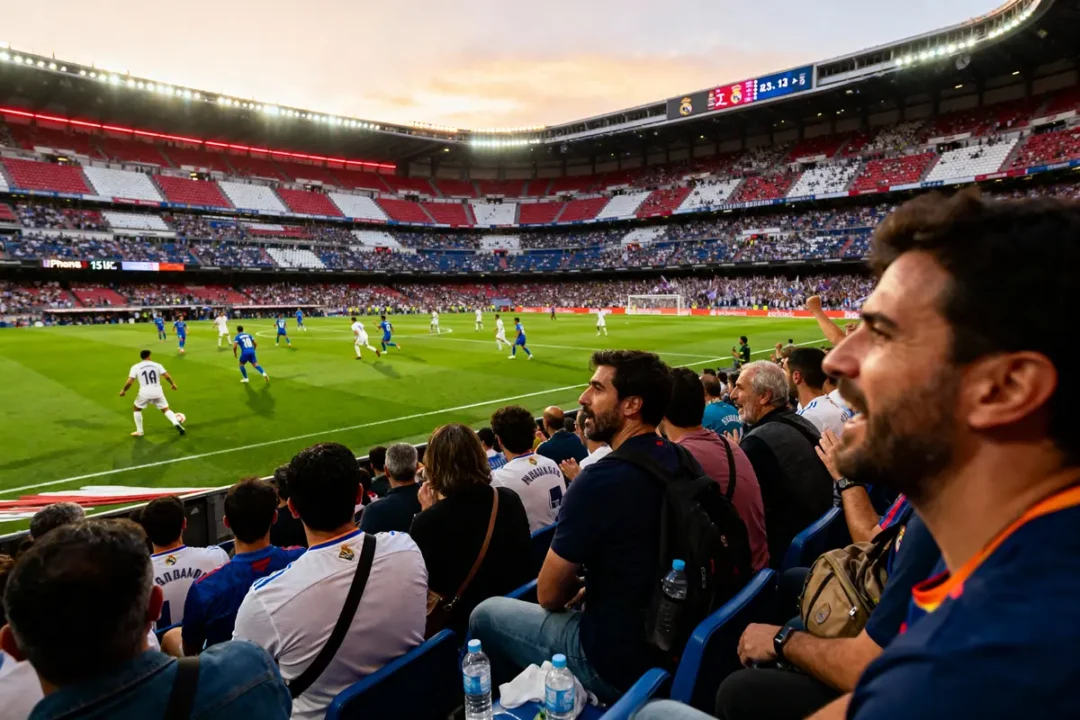 Spectateurs regardant un match de football au stade couvert, joueurs en bleu et blanc sur le terrain.