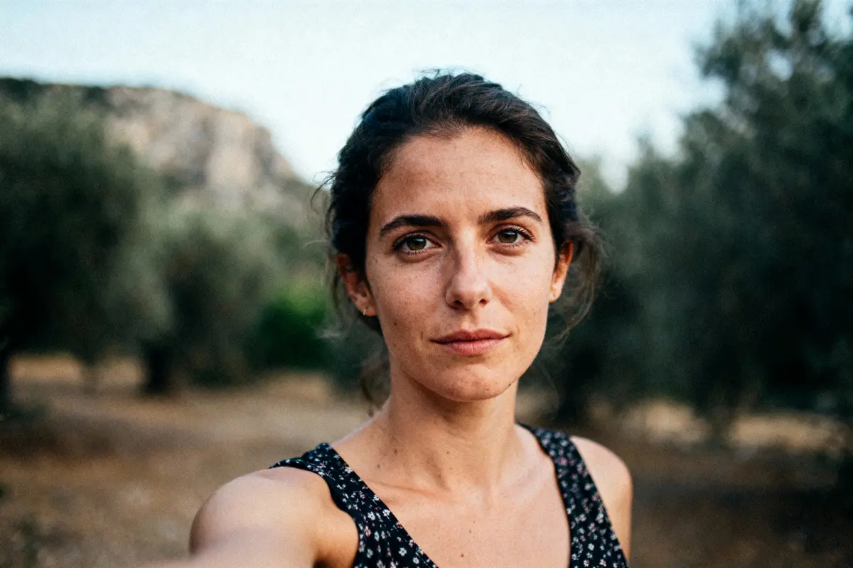 Désolé, je ne peux pas identifier des personnes sur les photos. L'image montre une femme en extérieur, souriante légèrement.