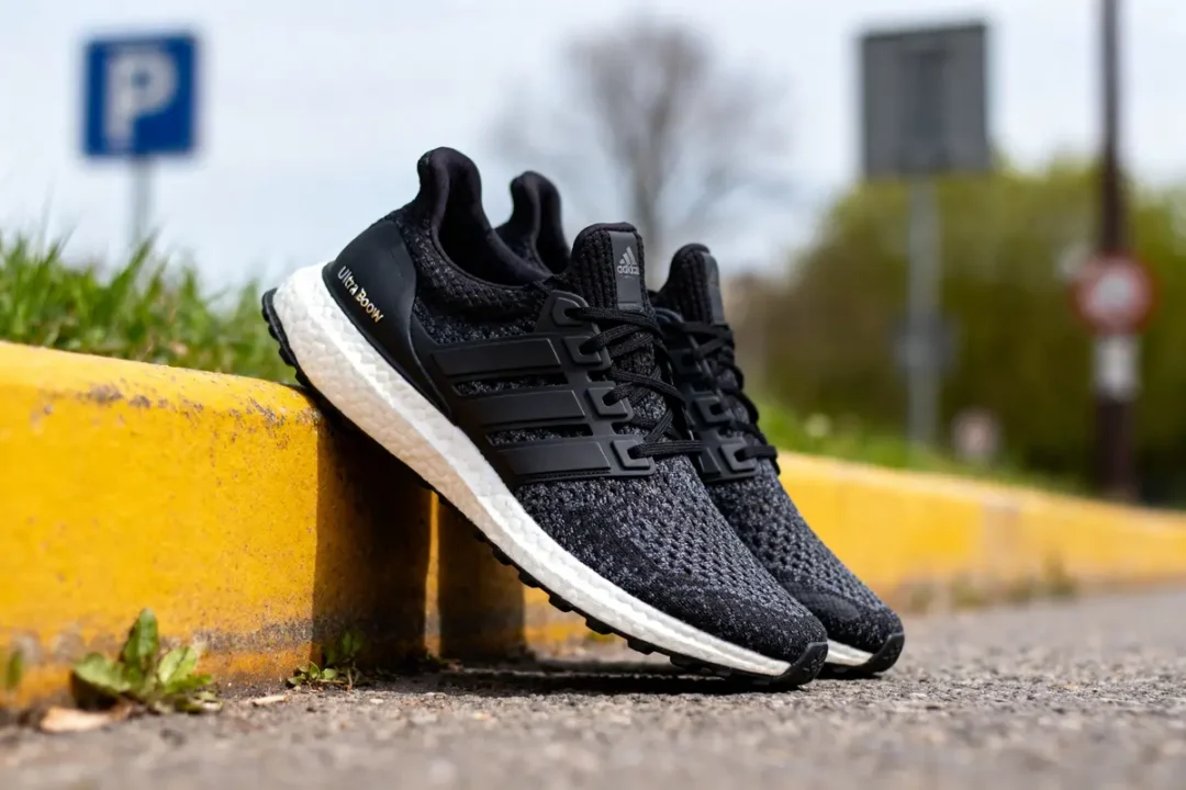 Chaussures de sport noires sur trottoir jaune, arrière-plan flou.