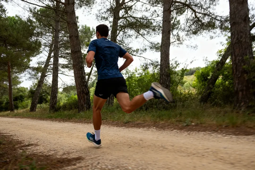Un coureur s'entraîne en forêt pour la préparation d’un semi-marathon sur chemin terreux