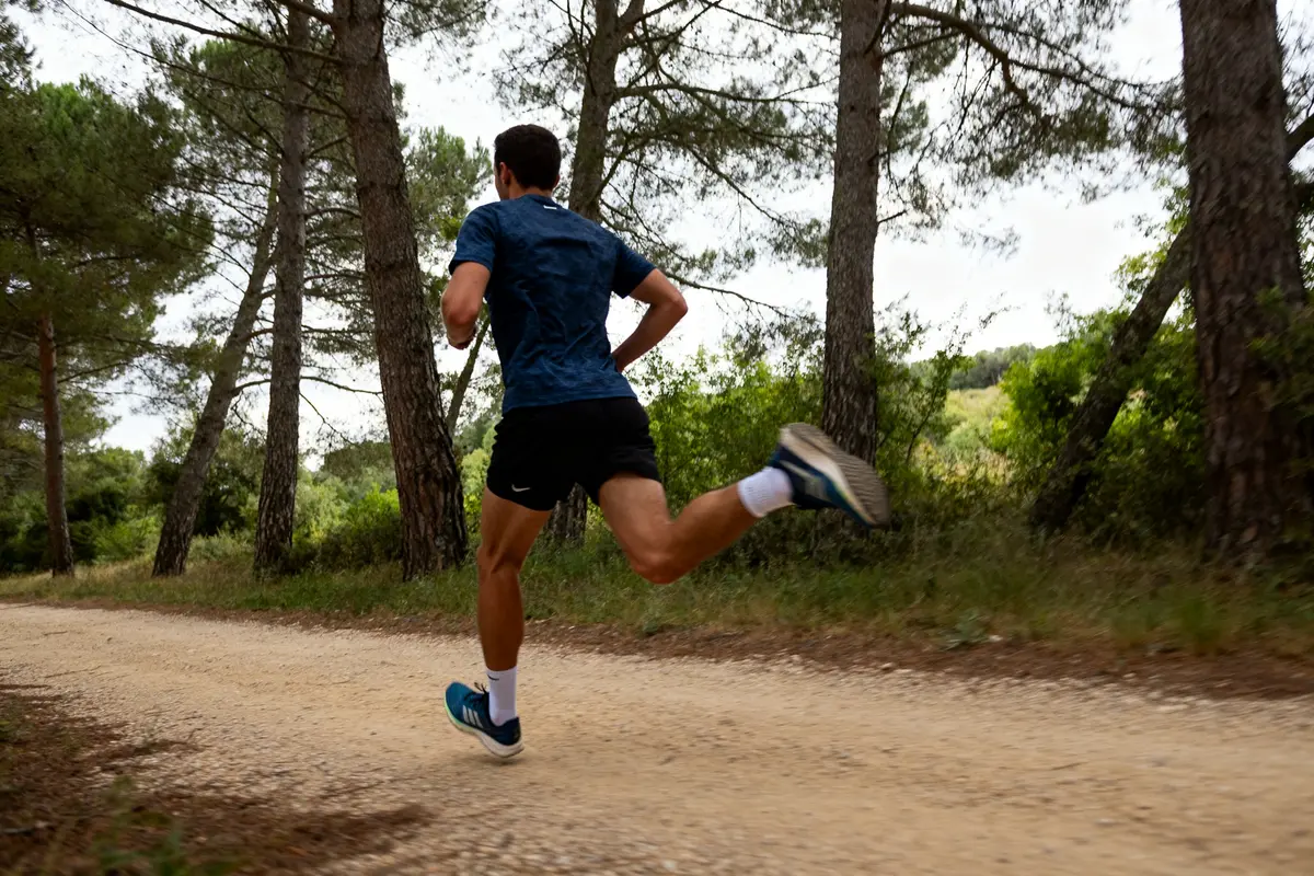Un coureur s'entraîne en forêt pour la préparation d’un semi-marathon sur chemin terreux