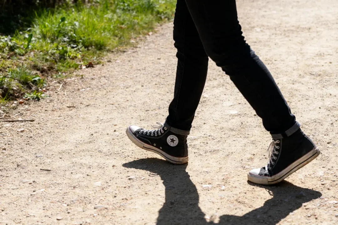 Personne marchant sur chemin, chaussures noires, 20000 pas en km parcourus quotidiennement