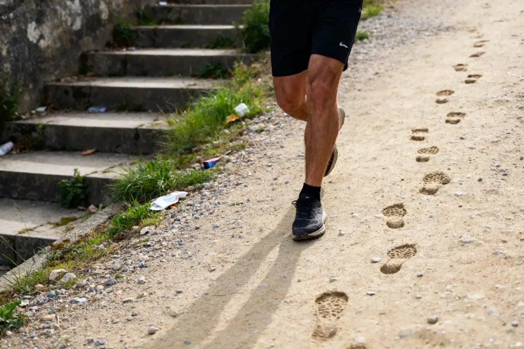 Homme courant sur sentier poussiéreux, trace ses empreintes équivalant à 20000 pas en km