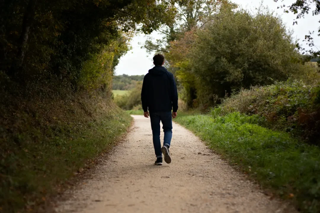 Homme marche sur un sentier forestier évoquant 20000 pas en km.