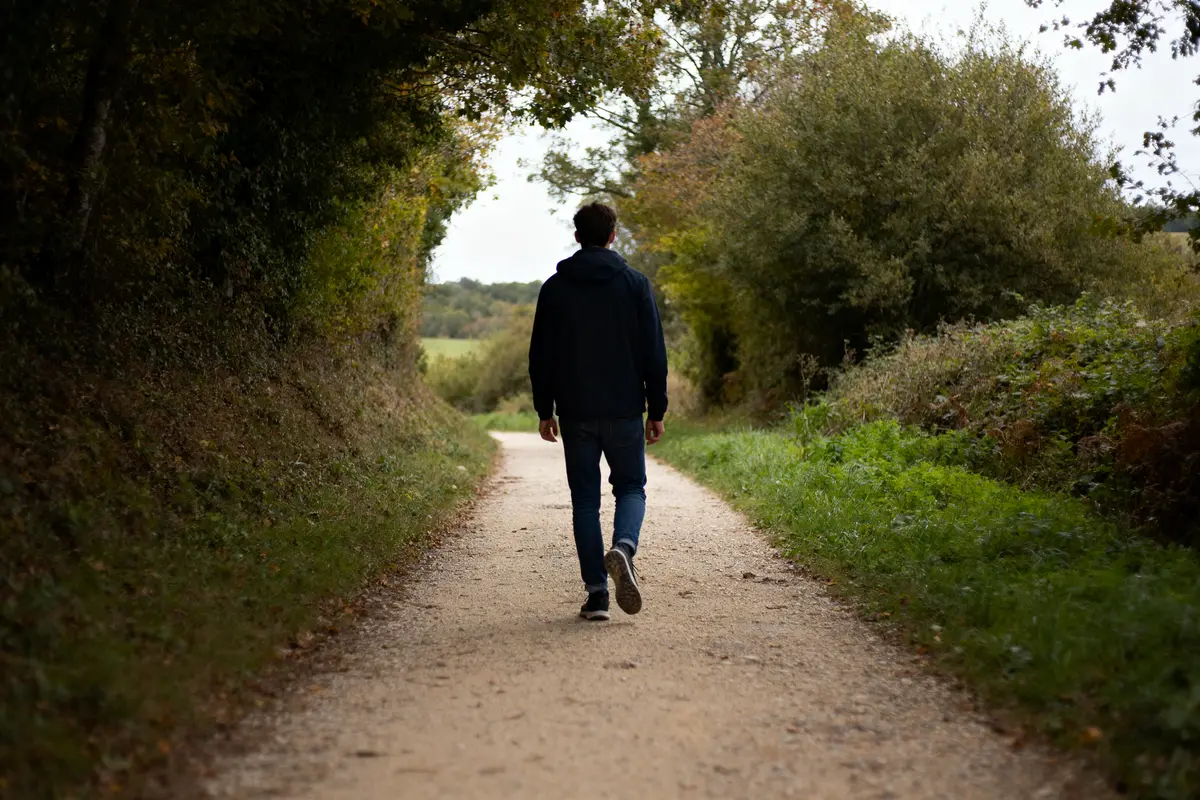 Homme marche sur un sentier forestier évoquant 20000 pas en km.