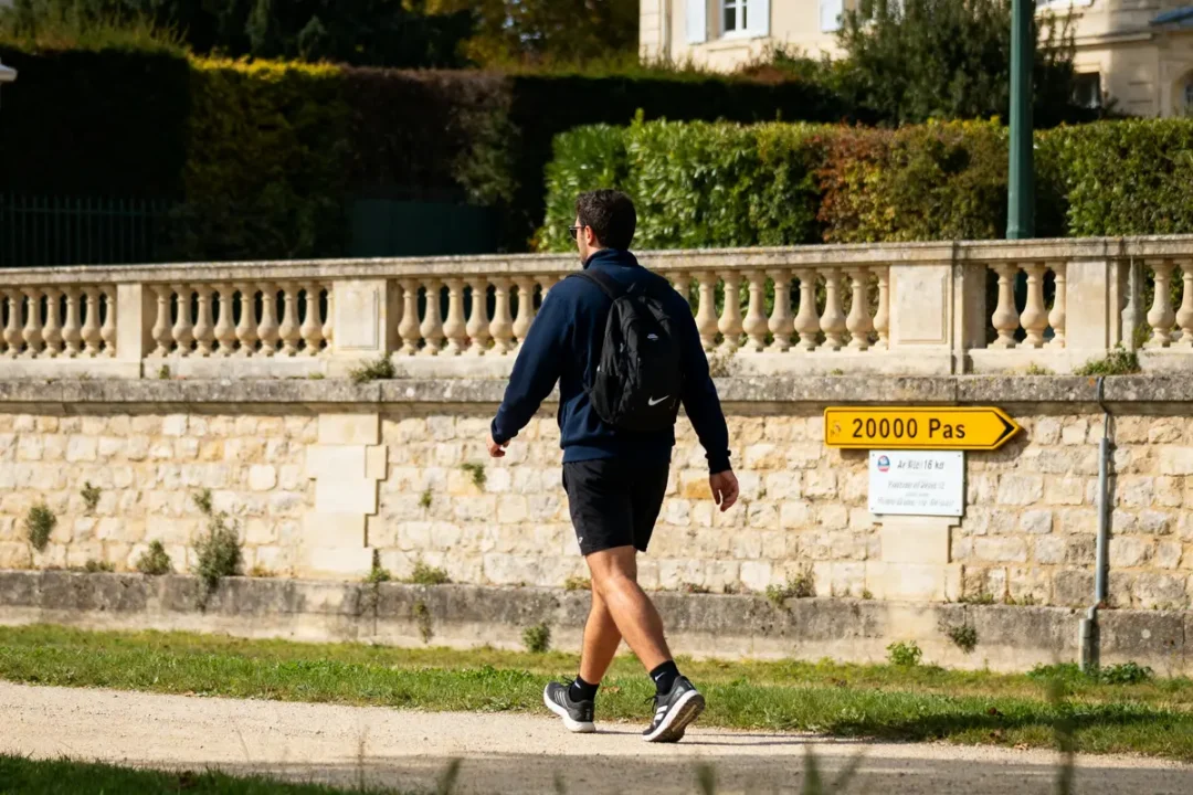 Homme marchant près d'un panneau indiquant 20000 pas en km dans un parc urbain