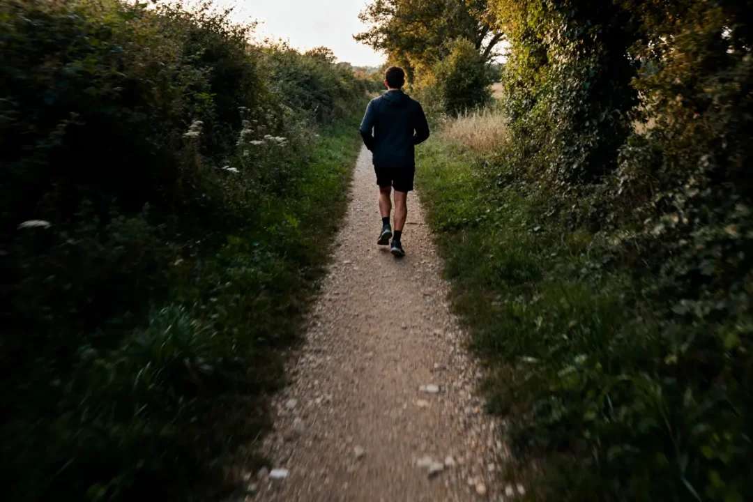 Homme marchant dans un chemin forestier évoquant 20000 pas en km pour la santé