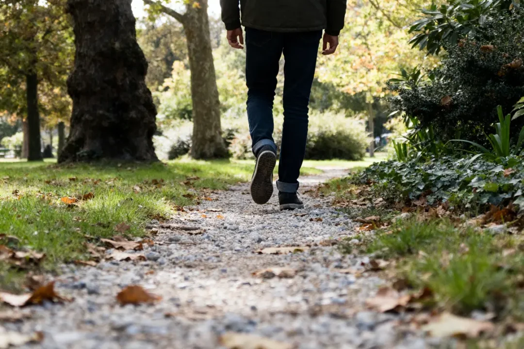 Homme marchant sur un chemin forestier illustrant 20000 pas en km en automne