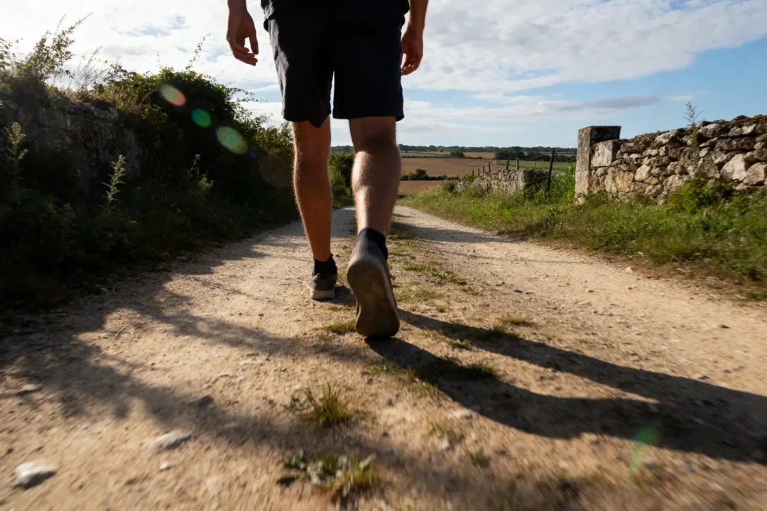 Marcheur sur chemin rural ensoleillé pour atteindre 20000 pas en km quotidiennement