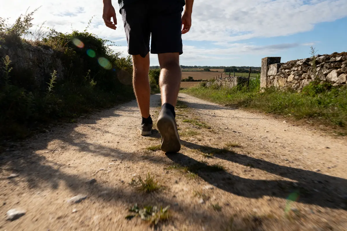 Marcheur sur chemin rural ensoleillé pour atteindre 20000 pas en km quotidiennement