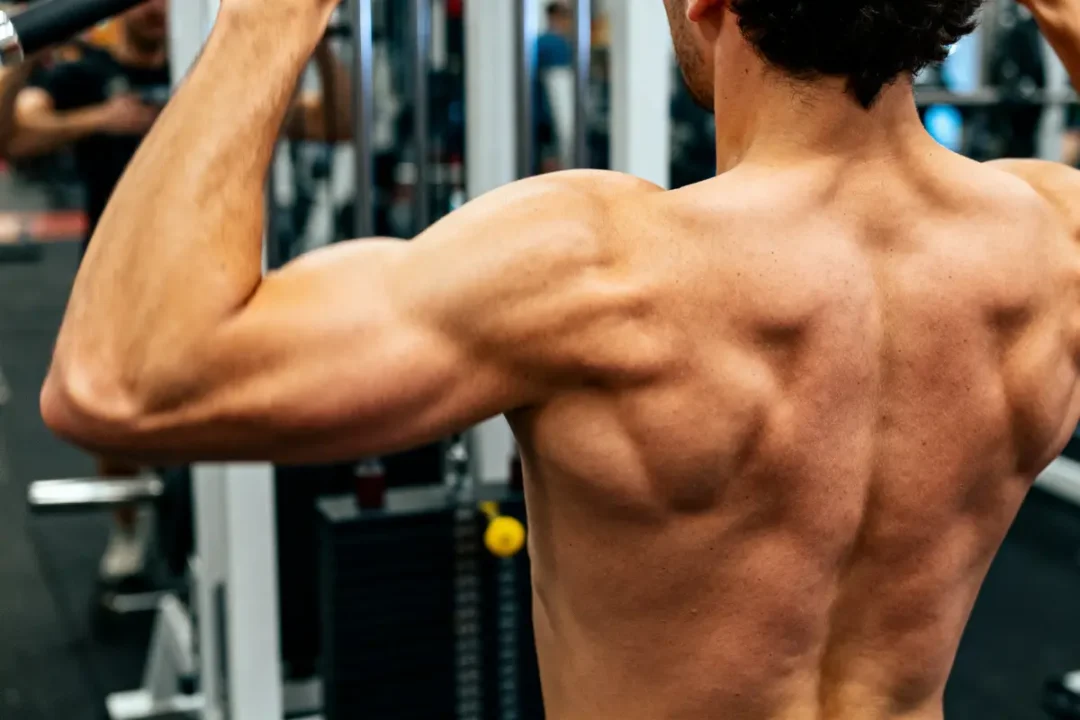 Homme musclé effectuant un exercice de tirage vertical dans une salle de sport