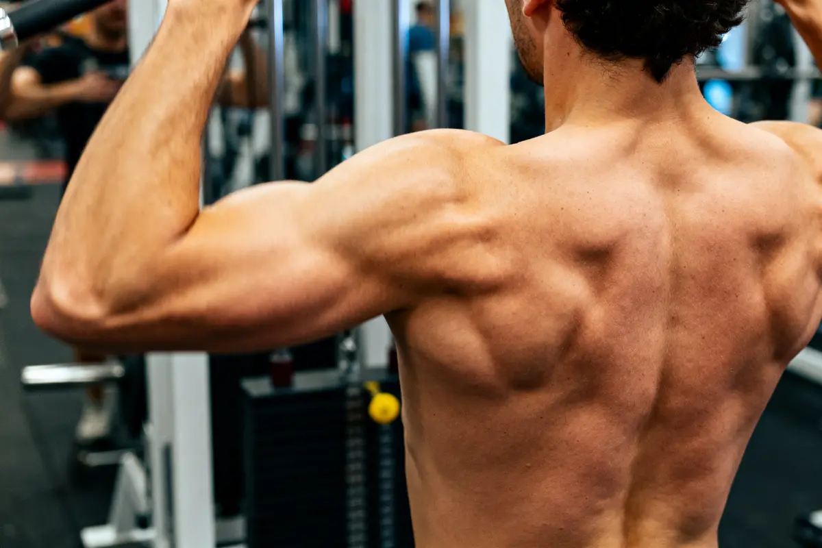 Homme musclé effectuant un exercice de tirage vertical dans une salle de sport