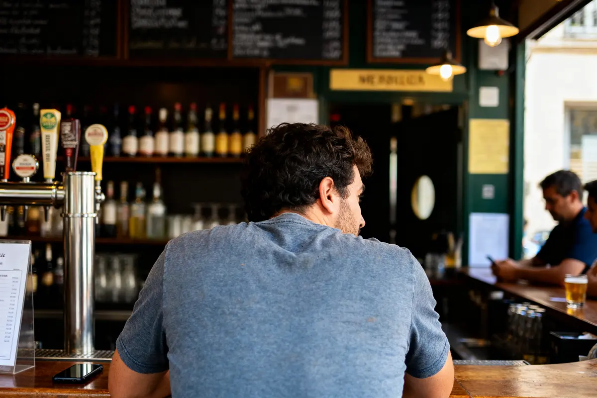 Homme assis au bar dans le bas du dos observant l'intérieur du pub