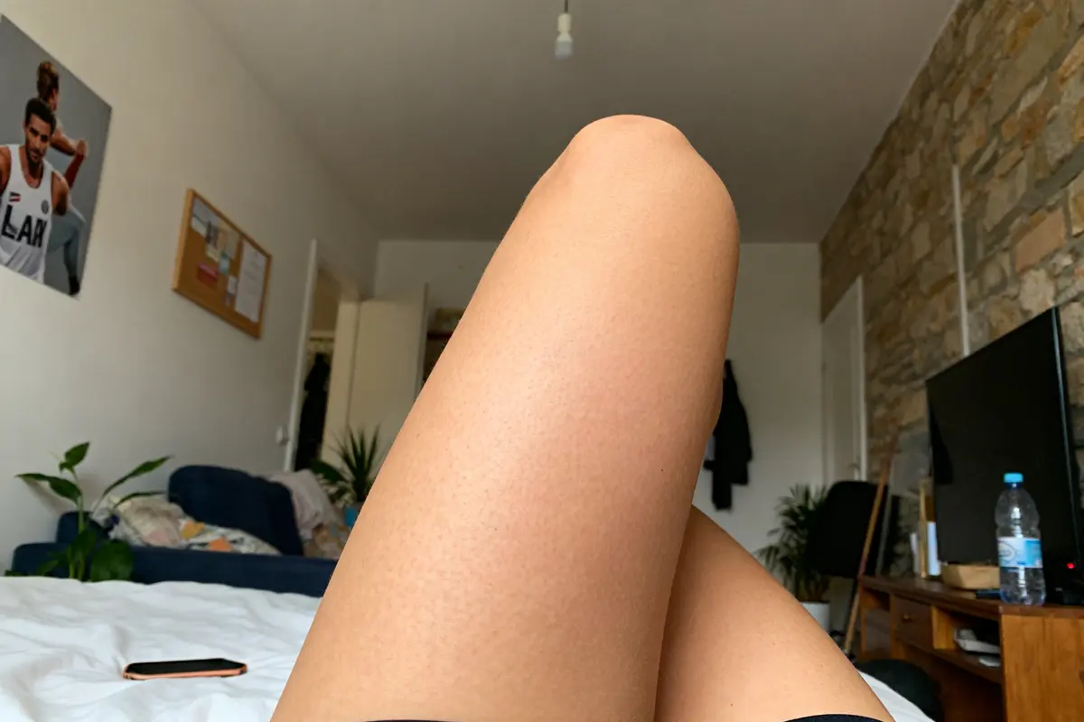 Jambes allongées sur lit illustrant cellulite avant après sport dans chambre moderne
