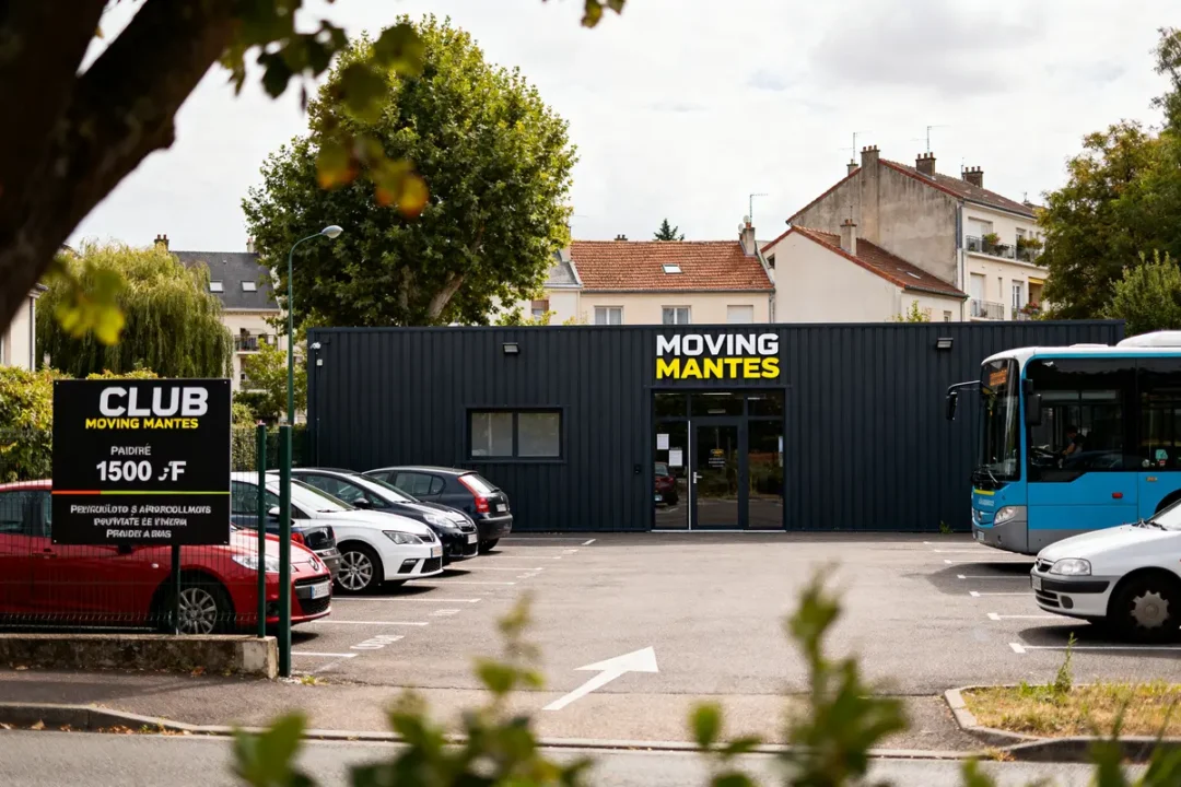 Bùtiment du club Moving Mantes avec parking et bus devant des maisons résidentielles