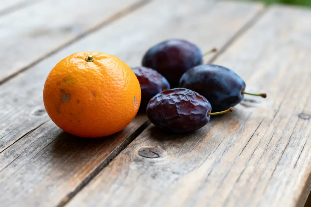 Mandarine et prunes sur table en bois, source de fruit fibre naturelle