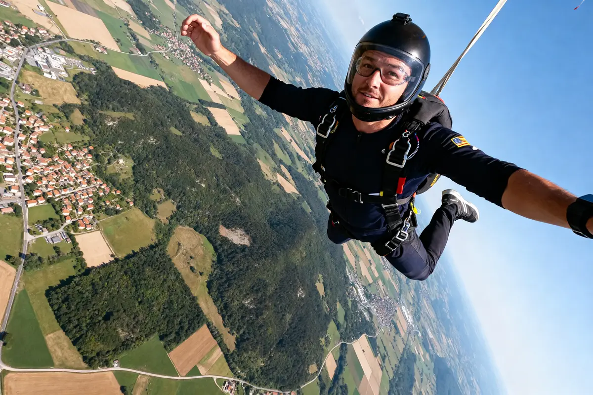 Une personne effectue du parachute diving au-dessus d'un paysage rural en journée ensoleillée
