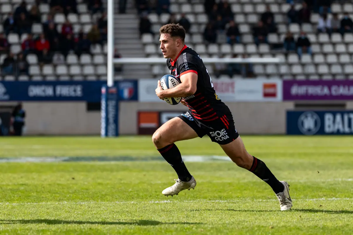 Joueur en action tenant le ballon poste rugby sur le terrain durant un match