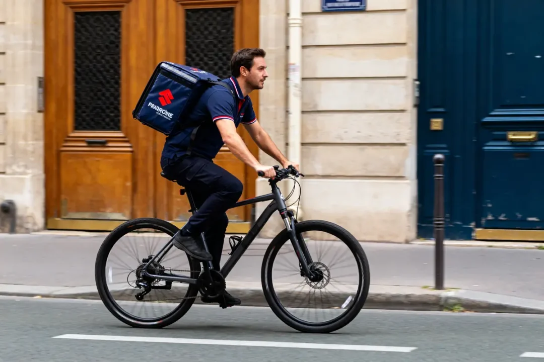 Livreur à vélo transportant un sac de livraison dans la rue comme un coureur urbain