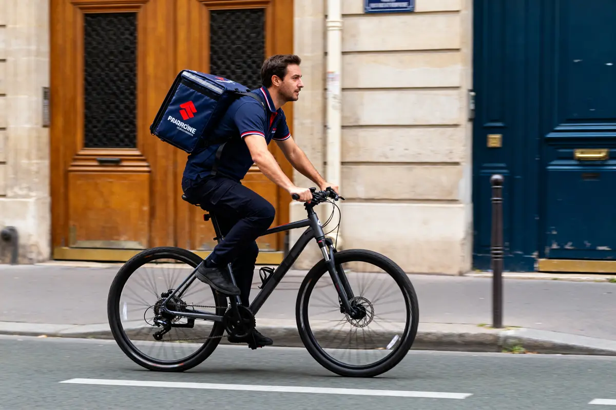 Livreur à vélo transportant un sac de livraison dans la rue comme un coureur urbain