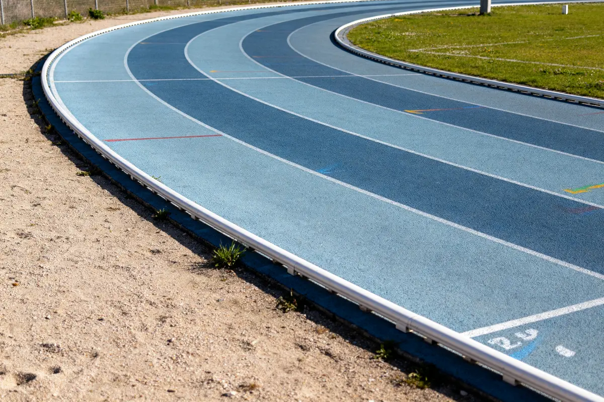 Virage d'une piste de course extérieure avec surface bleue et lignes marquées